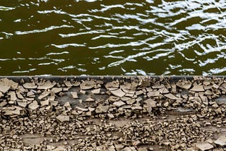 On the top half, green flowing river water, and on the bottom, fractured rock.