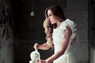 Woman in a dark room pouring tea in a cup