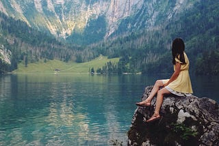 A woman looking at the mountain reflecting back.