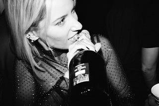 black and white photo of girl opening wine bottle with her teeth