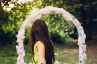 Woman reaching back holding hand of partner and looking toward wedding altar