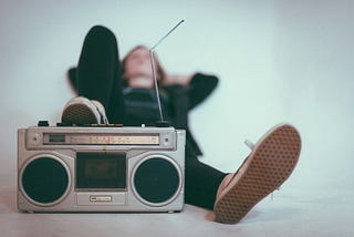 A young man lying down listening to a boombox