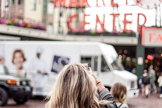 woman takes photo facing the entrance to market place