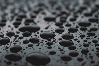 Zoomed in view of reflective water droplets on an opaque surface.