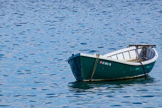 Small boat floating on the water. Nobody is aboard.