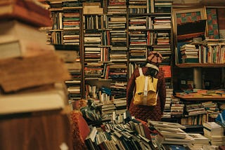 Young woman looking at a very overflowing and cluttered bookshelf