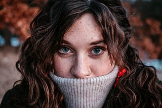 Woman with the neck of a jumper covering her mouth
