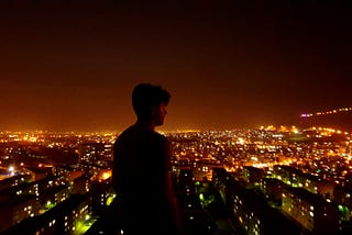 A man standing alone with the city in the background.