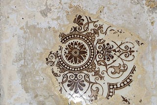 An ornate patterned tile emerging underneath layers of paint