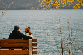 A couple sitting on a bench overlooking the lake.
