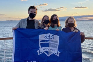 Foster holding a Semester at Sea flag with fellow voyagers Emily, Charlotte, and LLL Kathy.