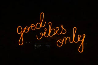 The words good vibes only lit up in orange on a black background.