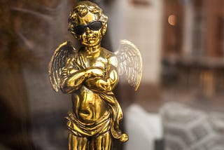 Trophy in the shape of a cherub figurine, folding its arms and wearing sunglasses