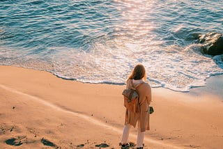 A girl daydreaming about his future life standing in front of sea waves