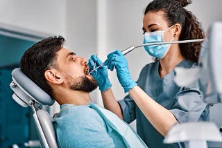 A male patient getting his teeth fixed by a female dentist