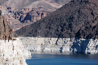 Photo of a lake flowing in between mountains. The mountains show a distinct waterline