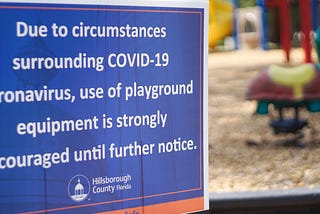 A sign posted next to a park warns children not to use playground equipment until further notice, because of COVID-19.