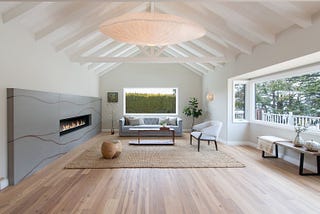 This living room features a custom concrete fireplace inlaid with copper, inspired by Japanese Kintsugi pottery. A glowing overhead light handmade from washi paper harkens a resemblance to whales and seashells, a quiet reference to the ocean nearby.