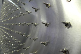 fisheye lens view of a shiny metal wall covered in simple metal on/off switches