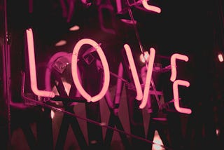 Pink neon lights create the word “love”.