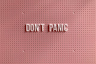 Pink sign saying “Don’t Panic”