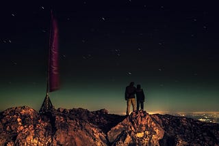 couple standing on mountain looking off into distance in wonder