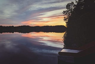A picture of a lake at sunset with a slide going into the water.