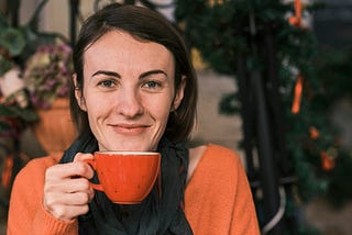 A smiling woman enjoys a cup of tea