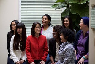 Image of the eight cofounders of Project Include (listed below) sitting casually in a group, smiling and looking at each other or at another camera