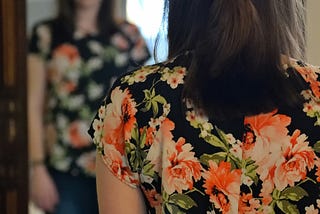 a woman wearing a floral top looking in a mirror