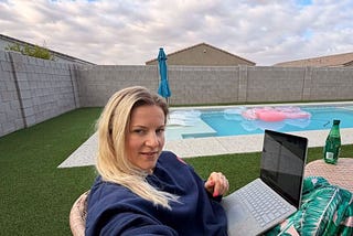 Woman working on a computer by the pool