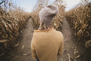 Woman in a wheat field wondering which path to choose.