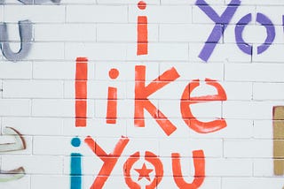 words i like you on white brick wall in different colours