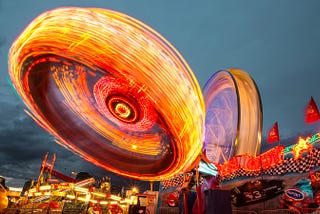two Ferris wheels photographed with a slow shutter speed to produce a blur of lights