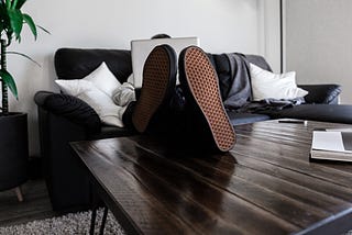 A man sitting on a couch with his feet up on the coffee table.