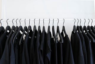 A clothing rack lined with various garments that are all black