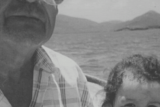 Gif with a black and white portrait of Thania Betancourt Alcazar as a child sitting next to her late grandpa Manuel on a boat. Fading into the front is a colored image of Thania’s hand holding her grandpa’s bumpersticker that says I heart democracy in spanish
