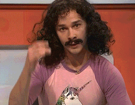 Shia Labeouf saying magic with long hair, a mustache and a unicorn tee shirt