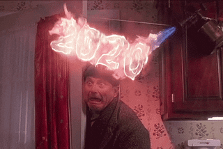 A gif of a man getting fire sprayed onto his head with the text “2020”