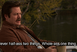 Ron Swanson from NBC’s Parks & Rec sits on a wooden deckchair with a cup of coffee and says to Leslie Knope: “Never half-ass two things. Whole-ass one thing.”