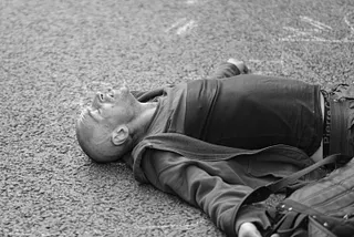 Exhausted man lying down in street.