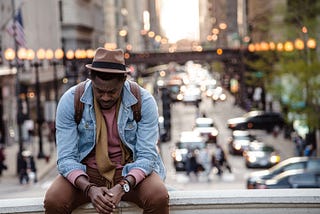 A thinking man sitting in front of a vibrant city scene.