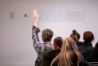 A crowd places bids at an auction on an unseen item of unknown value.