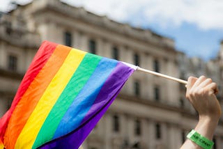 A hand waving a rainbow pride flag.