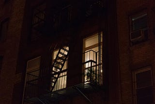 From the street, lights can be seen on in an apartment at night.