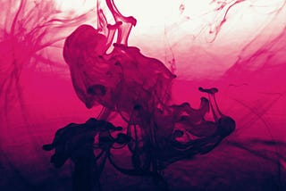 A dancing woman appears to emerge from a pool of dark pink liquid