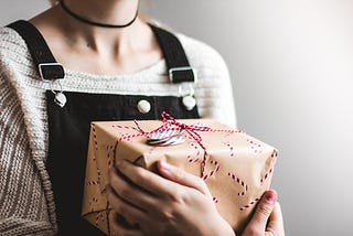 Woman holding a wrapped present in her arms.