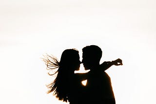 Silhouette of a woman and a man on the beach illuminated by the sunset.