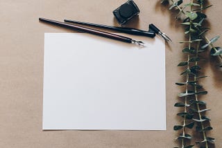 Fountain pen and blank piece of paper with eucalyptus leaves.