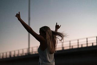 A woman throwing her arms up in the air in celebration.